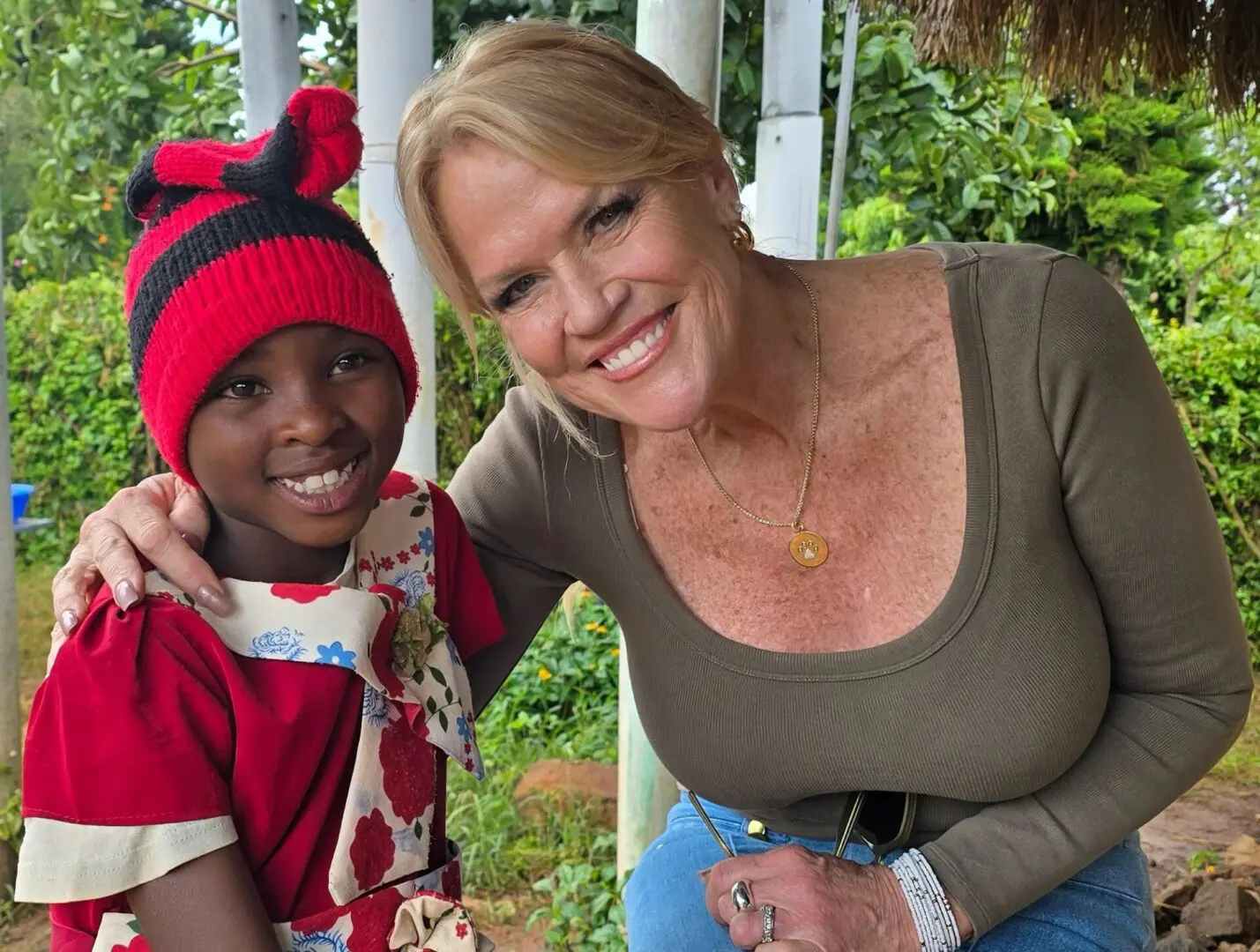 Smiling woman hugging girl in red hat