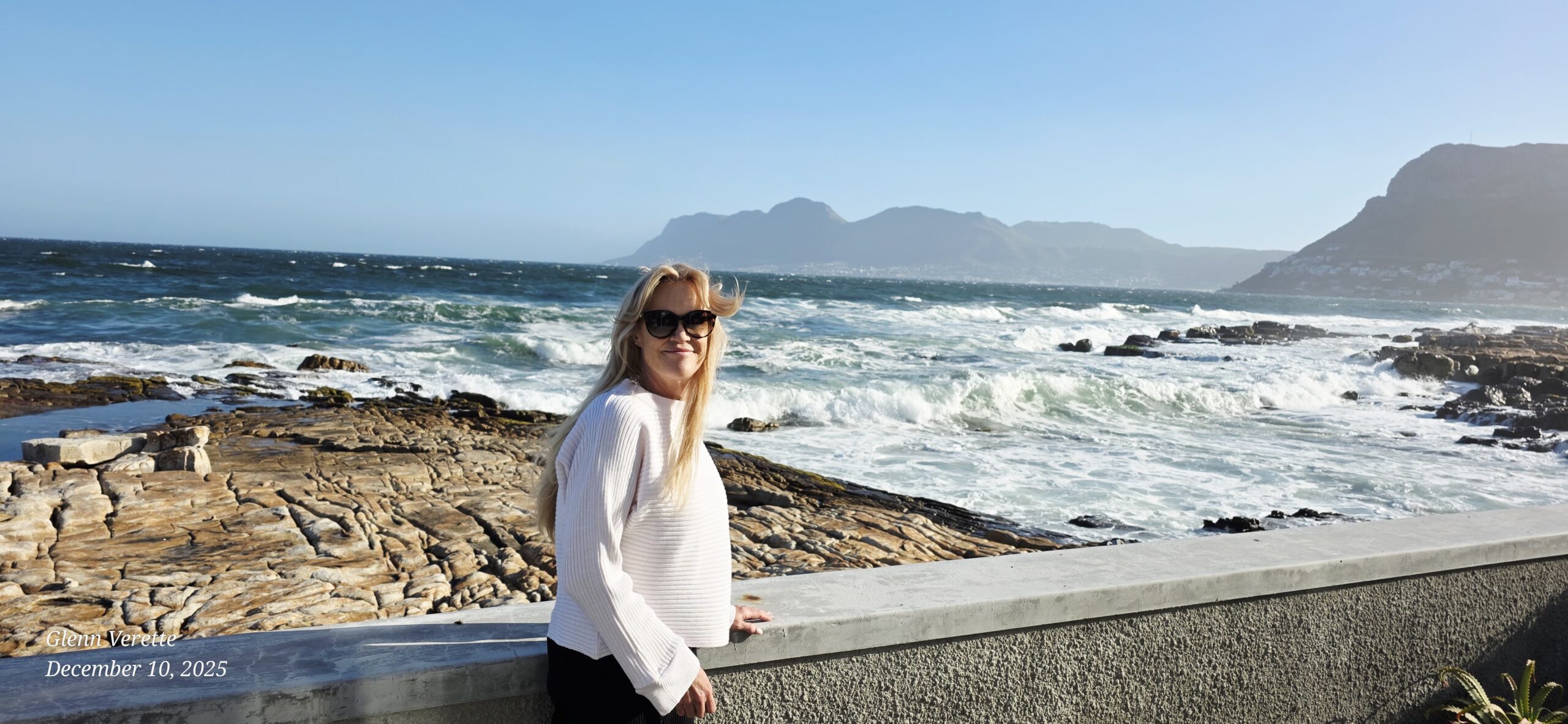 Woman in sunglasses by rocky ocean shoreline